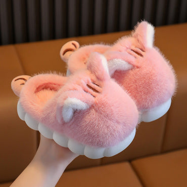 Pink fuzzy slippers with animal ears on a brown surface